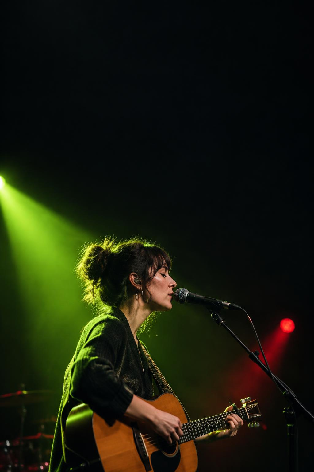 Musician performing beneath a lime stage spotlight